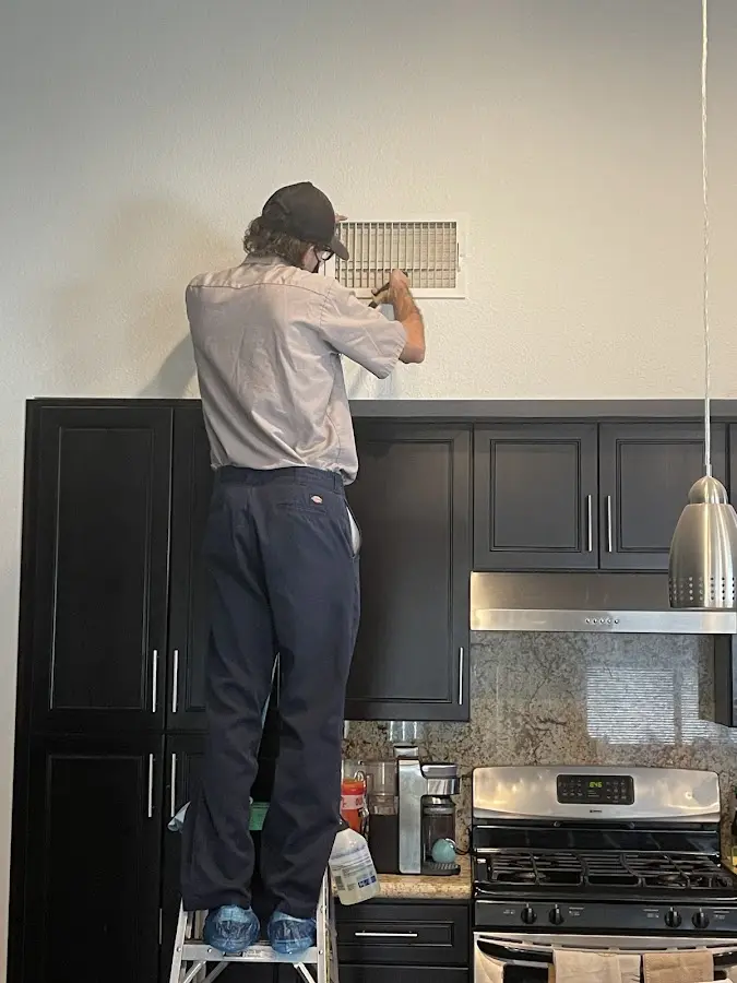 Technician inspecting an air vent during HVAC service in Shelburne